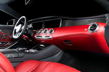 Fototapeta na wymiar Red luxury modern car Interior with steering wheel, shift lever and dashboard. Clipping path. Detail of modern car interior. Automatic gear stick. Part of leather seats with stitching in expensive car