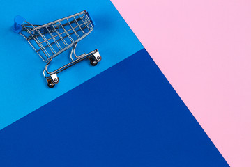 Mini shopping trolley cart on pastel pink, light blue and navy color background. Online shopping, buy, sale, discount concept