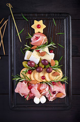 Antipasto platter with ham, prosciutto, salami, cheese,  crackers and olives on a wooden background.  Christmas table. Top view, overhead