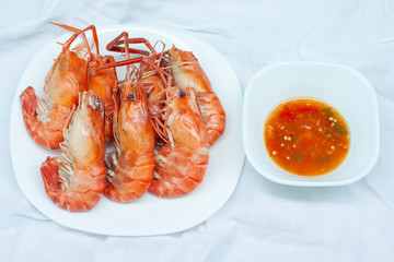 Steamed shrimp with seafood sauce on white tablecloth.