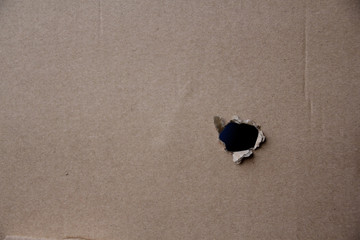 empty blank cardboard form, craft paper, hole with roughly torn edge, concept of secrecy, tracking, spying, blank for the designer, close-up, copy space