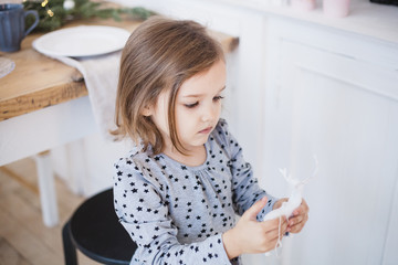 Little girl holding decoration for Christmas tree, Christmas interior, preparing for Christmas and new year, home decoration