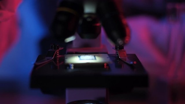 researcher in  scientific and technical laboratory with neon light examines ultra modern computer processor through microscope. Scientific industrial research. concept of modern technological future