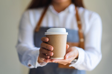A waitress holding and serving a paper cup of hot coffee in cafe