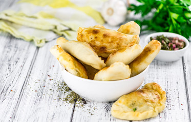 Wooden table with Empanadas (detailed close-up shot; selective focus)