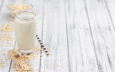Portion of healthy Oat Milk on an old wooden table (selective focus; close-up shot)