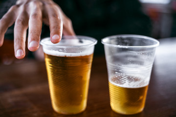 Two plastic glasses with beer stand side by side