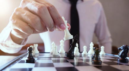 Closeup photo of businessman playing chess and beating black king