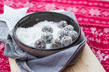 Sweet vegan coconut, cocoa, banana, dates, nuts energy protein balls. On Christmas table cloth background. Vegetarian healthy dessert food. 