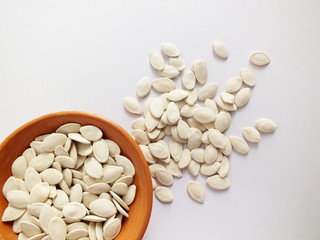 Dry pumpkin seeds  in terracotta cup on white background.