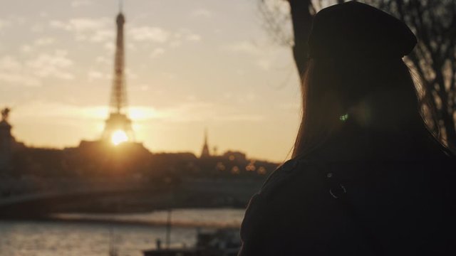 Rear view happy thoughtful blogger woman with camera watching epic sunset over Eiffel Tower in autumn Paris slow motion.