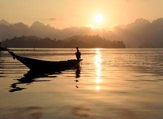 Silhouette scene of long tail boat during morning sunrise in Ratchaprapha Dam at  Khao Sok National Park, Surat Thani, South of Thailand.