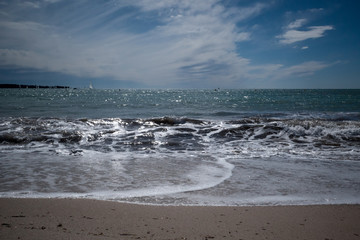 Welle läuft sanft am Sandstrand aus