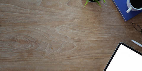 Top view of vintage workplace with copy space, mock-up tablet and office supplies on wooden table
