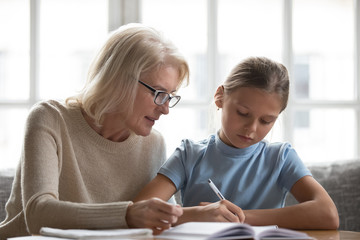 Loving grandmother help granddaughter with school assignment