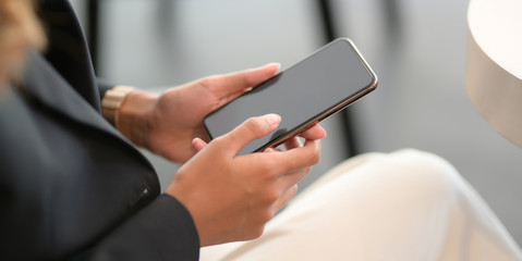 Cropped shot of young businesswoman holding smartphone in her office