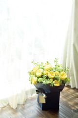 beautiful yellow English roses flower bouquet on wooden table next to window with sun light, copy space