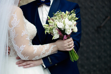 Hands and rings on wedding bouquet