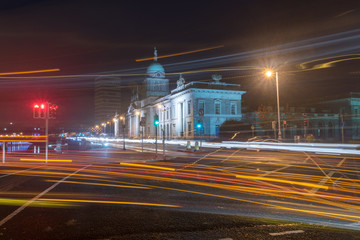 Blurred motion long exposure lines light of car headlamps headlights at night. Street view of city center of Dublin with The Custom House in background in Dublin, Ireland.