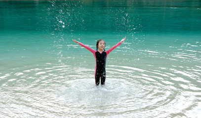 Happy young Asian girl in pink skin suit playing on the beach, Surin Island, North Andaman, south of Thailand