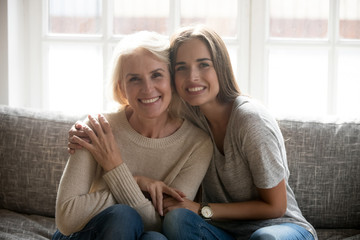 Smiling senior mom posing at home with adult daughter