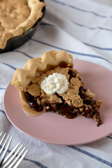A piece of homemade Chocolate Walnut Derby Pie on a pink plate, low angle view. Close-up.