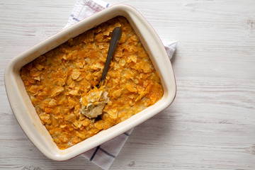 Home-baked Funeral Potatoes Casserole in a dish over white wooden background, top view. Flat lay,...
