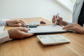 Car dealership provides advice about insurance details and car rental information and delivers the keys after signing the rental contract