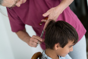 Obraz na płótnie Canvas Senior woman cutting boy's hair