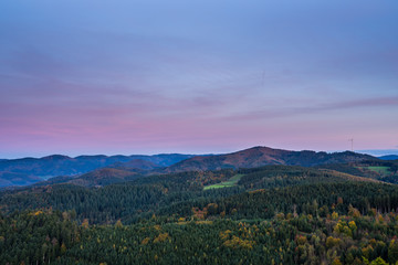 Germany, Endless untouched black forest nature landscape of forest covered hills and mountains under red glowing sky after sunset, aerial view above
