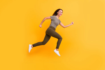 Fototapeta na wymiar Full size profile side photo of excited enthusiastic girl jump run fast feel content candid emotions wear stylish clothes isolated over yellow color background