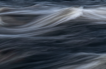 Close up from flowing water in long exposure shot. River rapids.