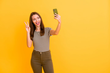 Portrait of cheerful positive girl blogging on spring holiday journey make selfie on cell phone show v-signs wear good looking outfit isolated over shine color background