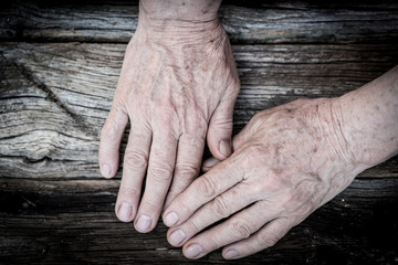 Senior hands on old wooden background