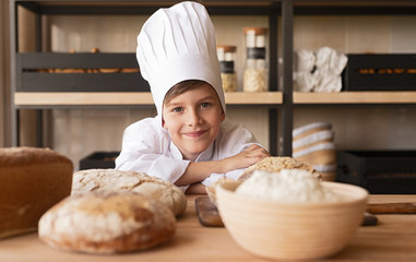 Happy little baker leaning on table
