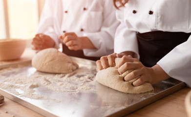 Crop baker apprentices kneading dough