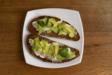 Fried brown bread with cottage cheese, avocado and basil