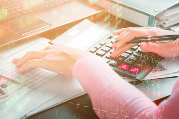 Business woman works at home and counts annual income using a calculator. The remote work, freelance, profit and market analysis concept. Double exposure with digital graphics and a girl in the office
