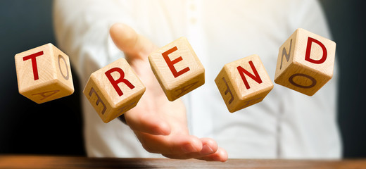 Cubes thrown by a man make up the words Trend. Popular and relevant topics. Evaluation methods....