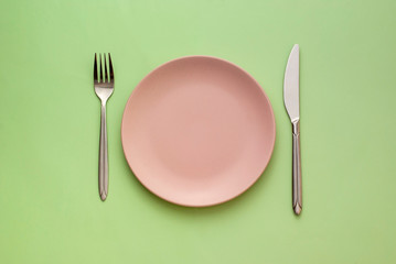 Empty pink plate with utensils on green
