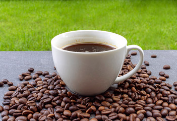 Coffee cop and coffee beans on the black stone in the garden.
