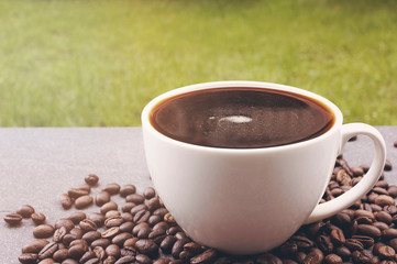 Coffee cop and coffee beans on the black stone in the garden.
