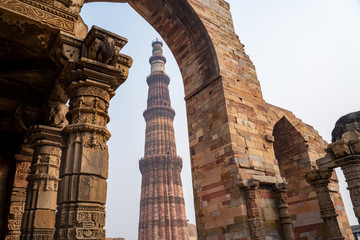 Qutub Minar pillar framed by an arch at at the historic site in New Delhi India
