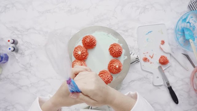 Step by step. Piping buttercream rosettes on top of round three-layer vanilla cake.