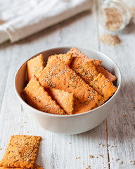 Cracker with lentil flour and sesame seeds in a cream bowl on a wooden table