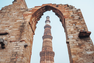 Fototapeta na wymiar Qutub Minar pillar framed by an arch at at the historic site in New Delhi India