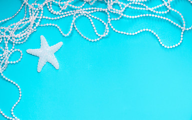 Fototapeta na wymiar on a turquoise background is a white starfish and pearls, a template for a postcard, an inscription form,space for text