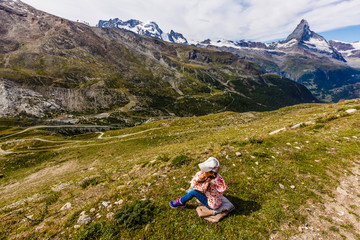 Naklejka na ściany i meble girl with a backpack in Swiss Alps with famous mount Matterhorn on background.