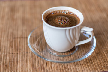 White cup of coffee on the bamboo napkin