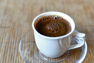 White cup of coffee on the bamboo napkin